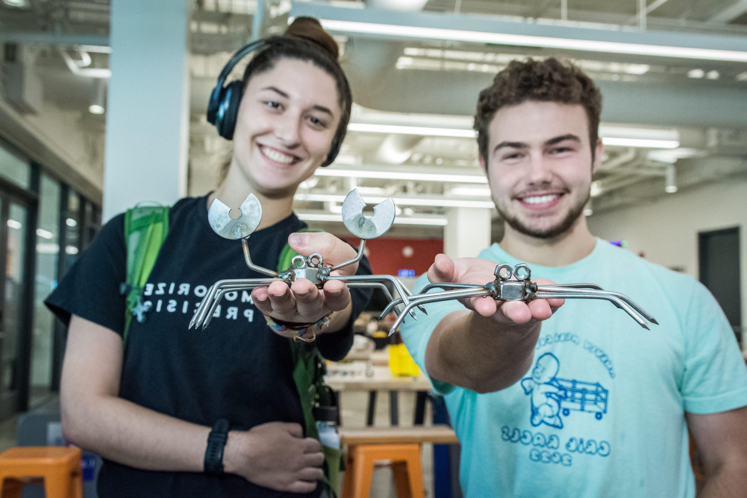 Students holding up welded metal crabs.